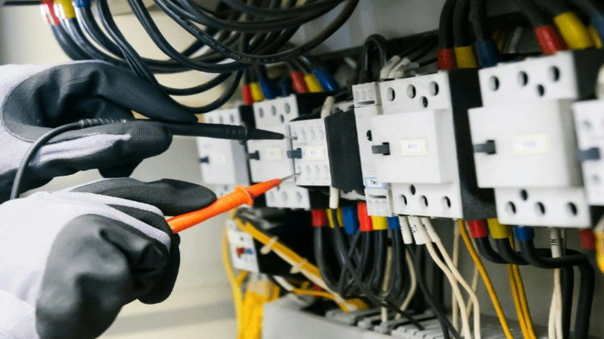 Eletricista ligando contatores em um painel
